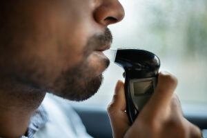 Man sitting inside car taking breath alcohol test