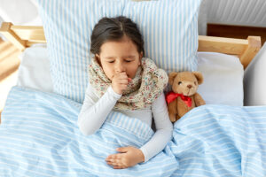 Young girl sick in bed with teddy bear