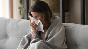 Sick woman resting at home and blowing her nose
