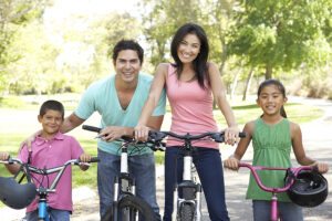 Young family riding bikes in a park