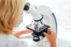 Lab technique analyzing sample under microscope
