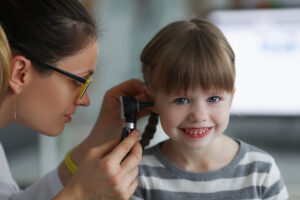 Medical professional examining a young girl's ear with an otoscope