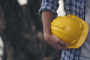 Picture of a construction worker holding a yellow hard hat.